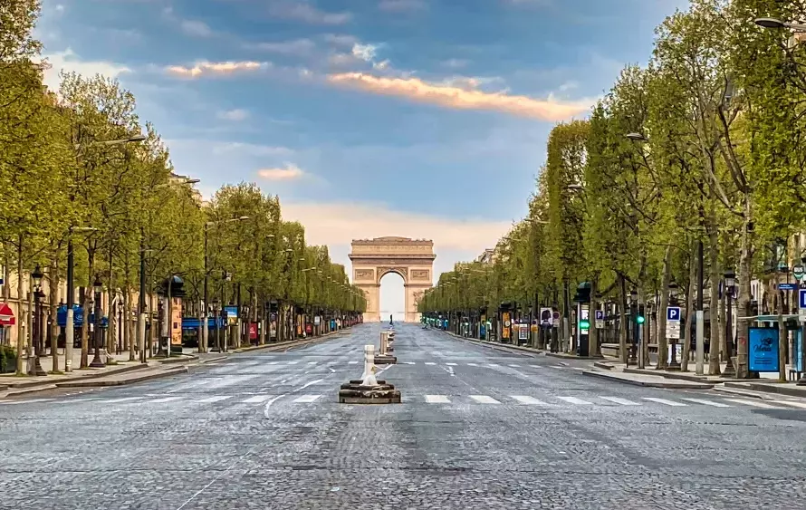 Vue des Champs-Élysées avec des allées et l'Arc de Triomphe au loin.
