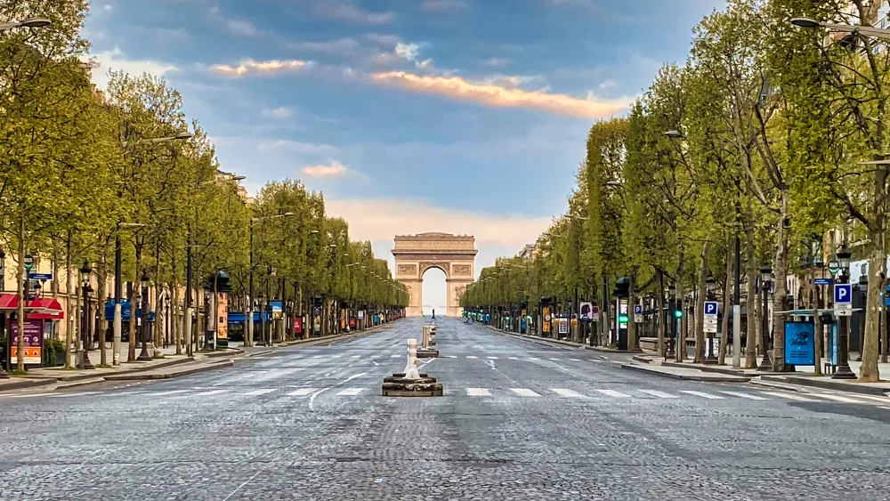 Vue des Champs-Élysées avec des allées et l'Arc de Triomphe au loin.