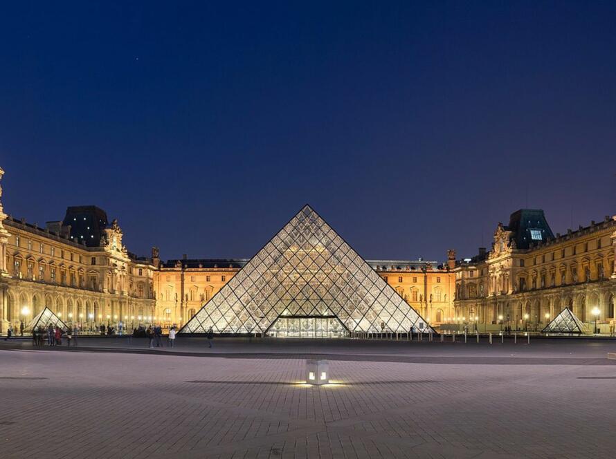 La pyramide du Louvre illuminée au crépuscule, reflet sur la cour Napoléon.