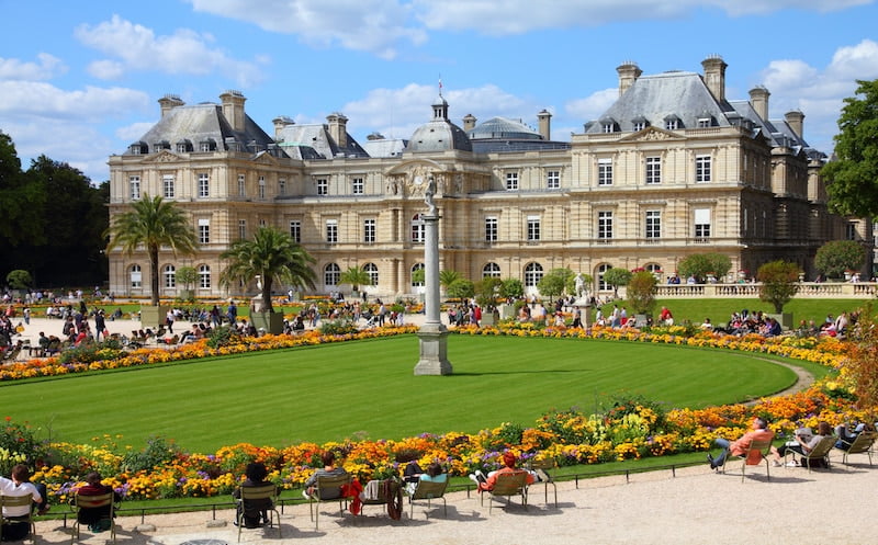 Vue des Jardins du Luxembourg avec un petit gazon et le bâtiment principal en arrière-plan.