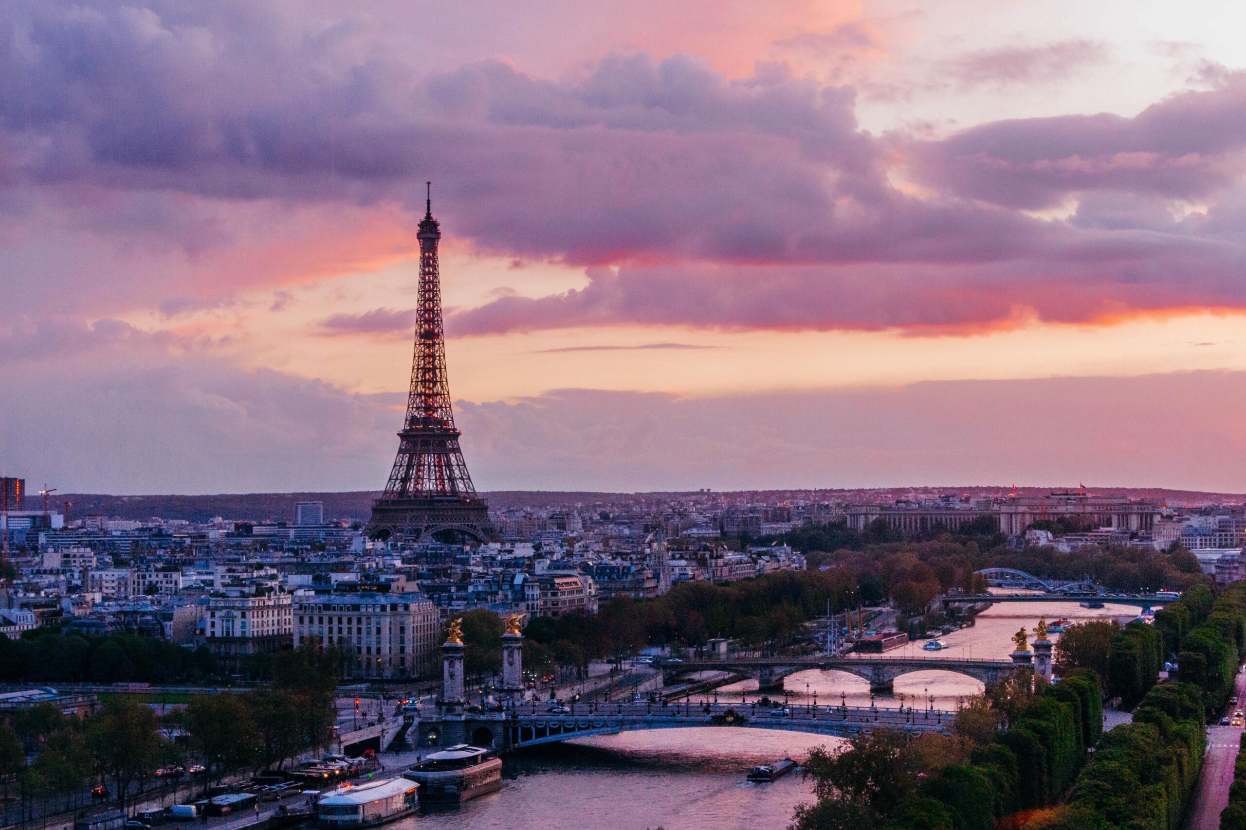 Vue panoramique de Paris au coucher du soleil avec la Seine, ses ponts et la tour Eiffel.