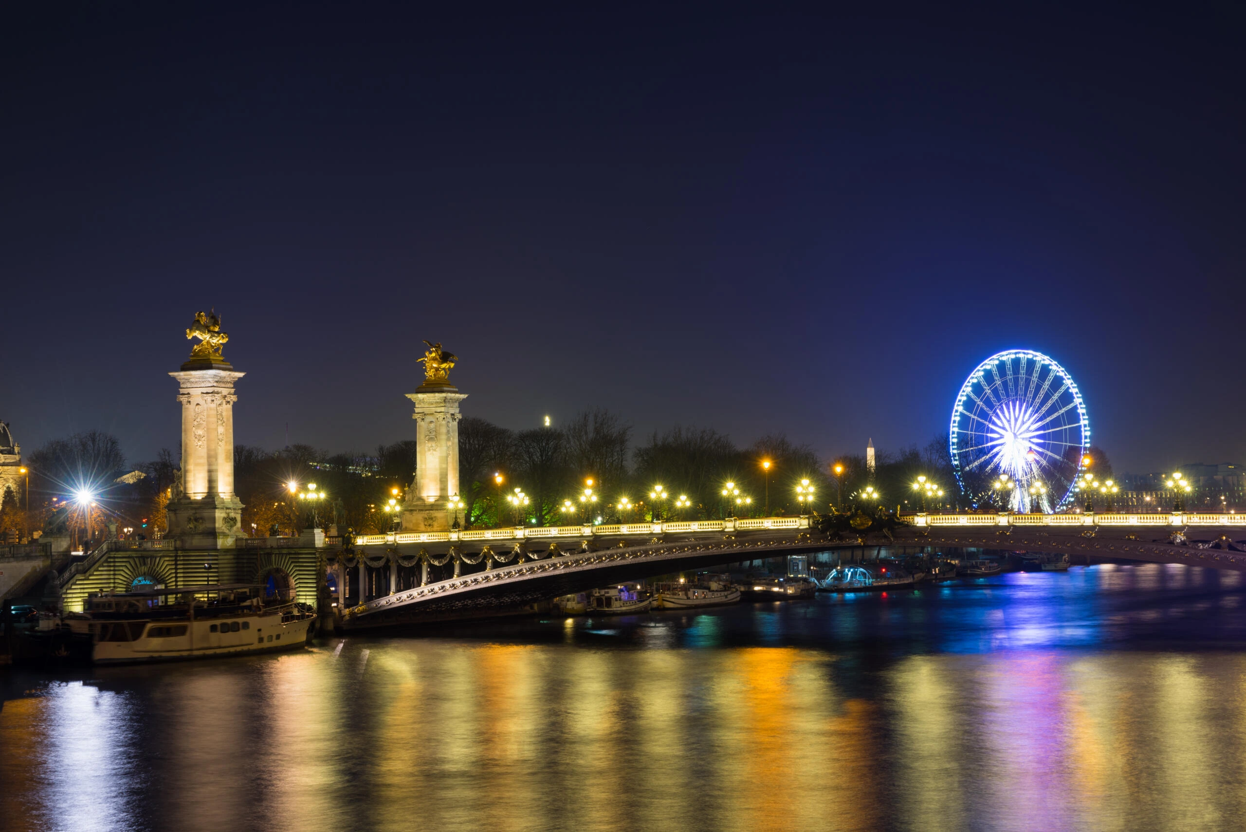 Pont Alexandre III illuminé la nuit à Paris, reflet doré sur la Seine.